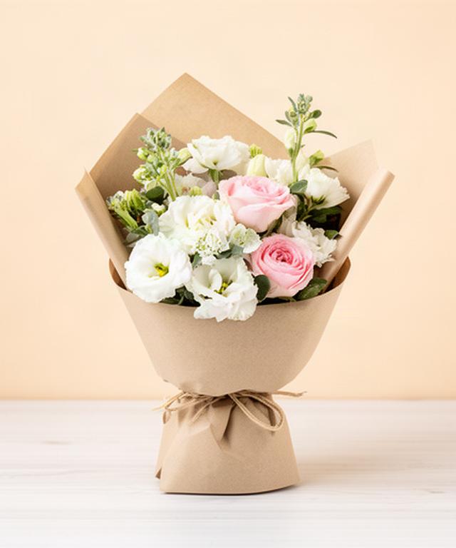 Ramo minimalista de flores blancas y rosadas envuelto en papel natural para un cumpleaños