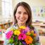 Profesora sonriente con un ramo de flores en un aula luminosa
